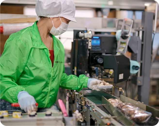 4番「納品」の様子。ベルトコンベアで流れてきたパック詰されたしいたけを女性スタッフが検品している。